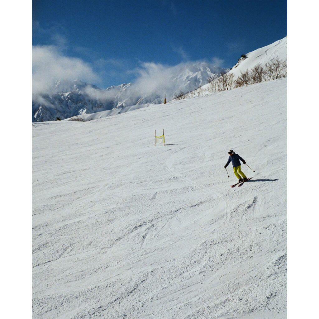 【Rollei35】雄大な山々をバックにターンを決めるスキーヤー。